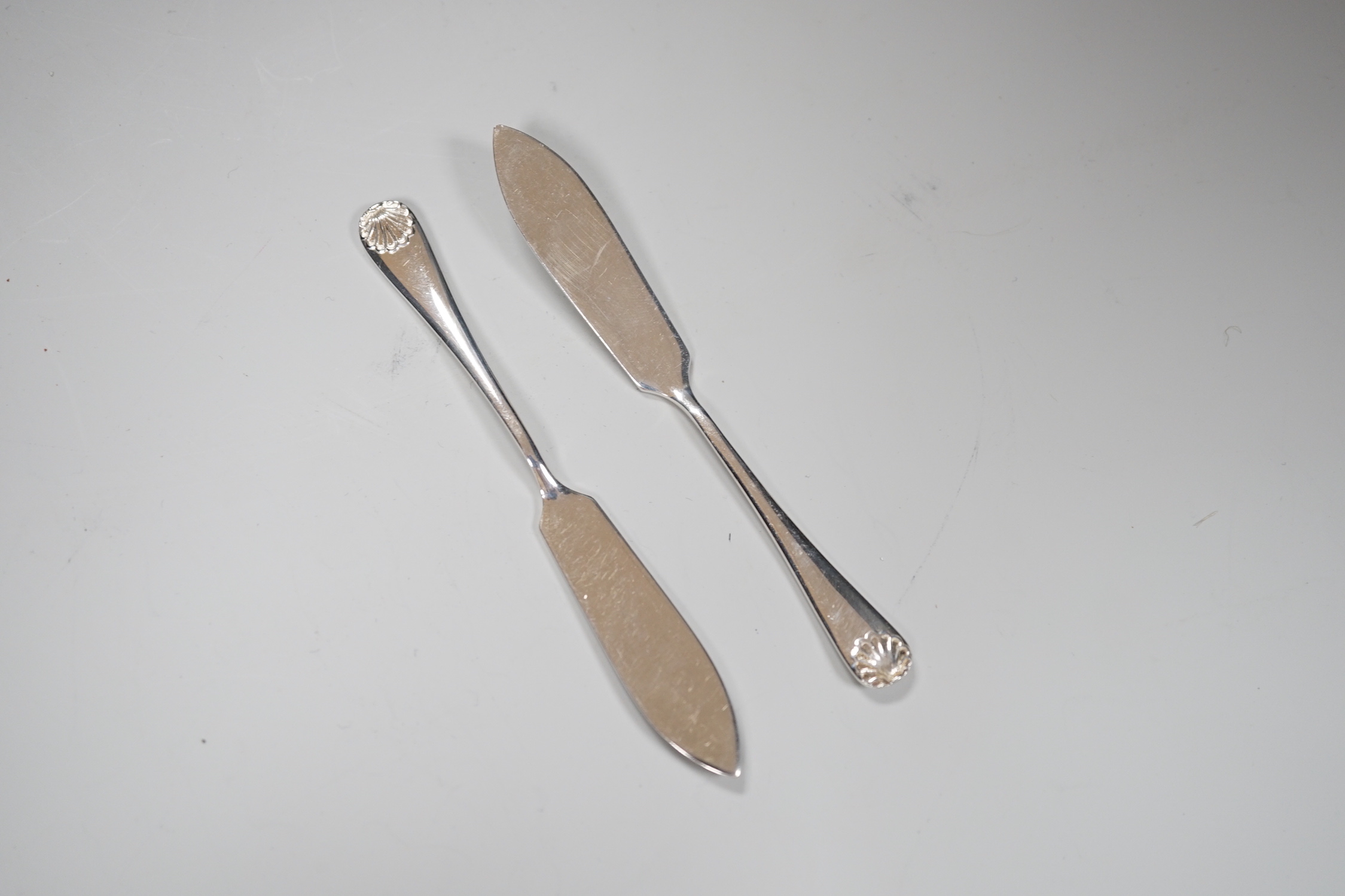 A pair of Elizabeth II silver scallop shell butter dishes, with frosted glass liners, 10cm, nett 94 grams, and matching butter knives, 21 grams